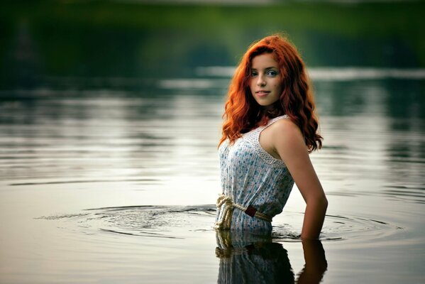 Rothaarige Mädchen im Wasser. Sie stieg in ihrem Kleid ins Wasser. Fotoshooting im Wasser