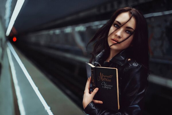 Mädchen in der U-Bahn mit Buch vom Wind weggetragen