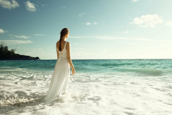 Photo de la jeune fille sur le dos sur la plage en robe longue