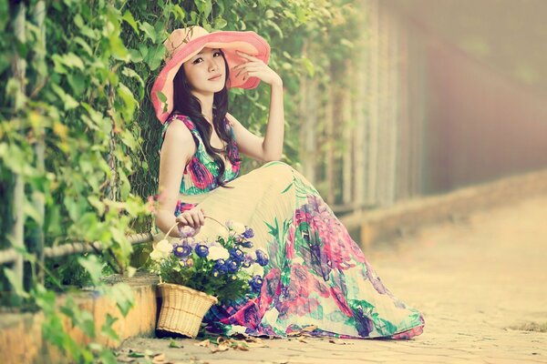 Chica asiática con una cesta en un vestido de flores