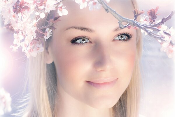 A girl s face with a smile on the background of spring blooming