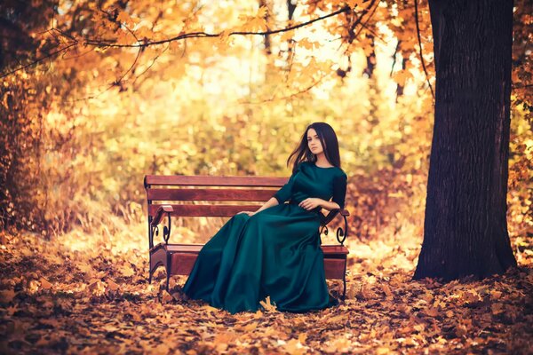 Ragazza romantica su una panchina nel parco autunnale