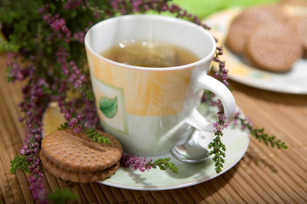 Tasse Tee mit Keksen auf einem Hintergrund von Blumen