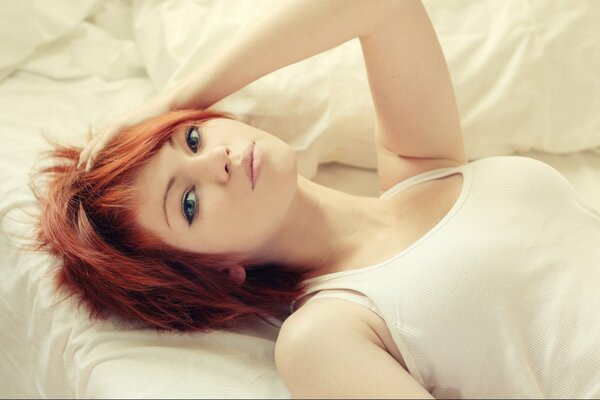 A red-haired girl is lying in bed