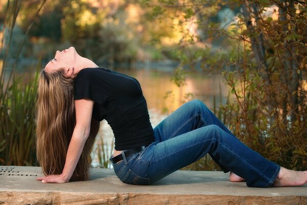 Ragazza in jeans vicino al lago con vita sottile