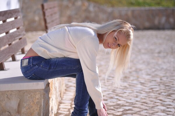 Sexy Mädchen in jeans sieht auf der Bank