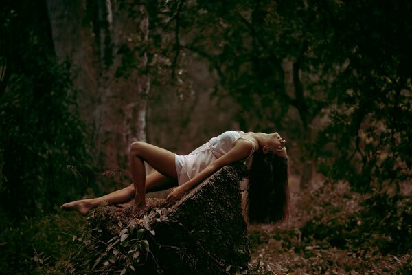 Foto de una chica en una piedra en el bosque