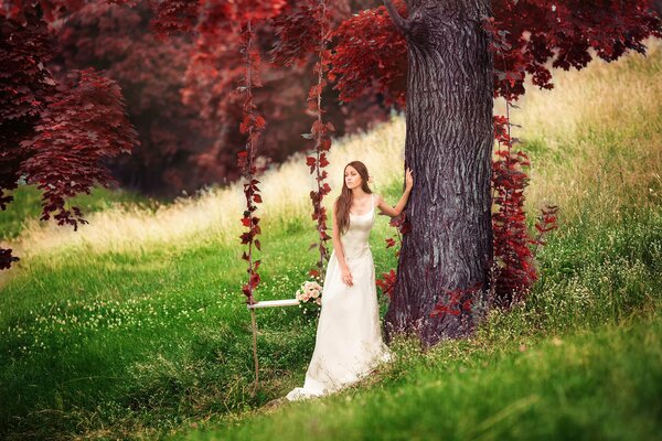 Ragazza in piedi accanto a un altalena e un albero