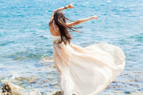 Fille sur fond de mer en robe blanche