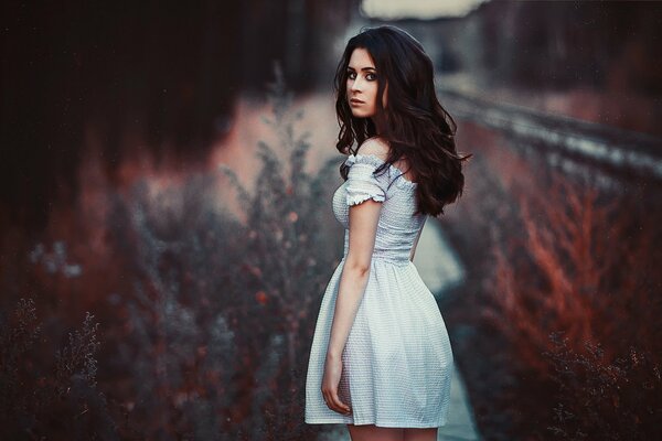 The girl is standing sideways in nature