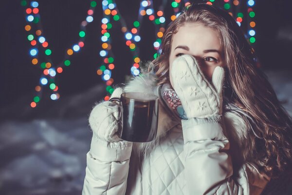 Mädchen mit einem Becher Heißgetränk bei Winterwetter