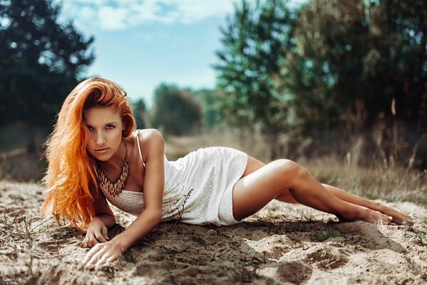 Pelirroja chica en vestido posando en la naturaleza