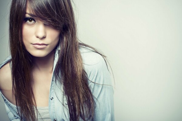 Fille avec de longs cheveux noirs en t-shirt et chemise sur fond Uni