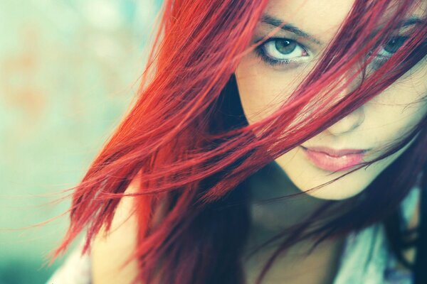 La cara de una chica con el pelo rojo y una mirada misteriosa