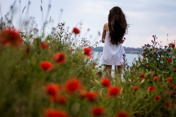 The girl standing with her back looks at the lake