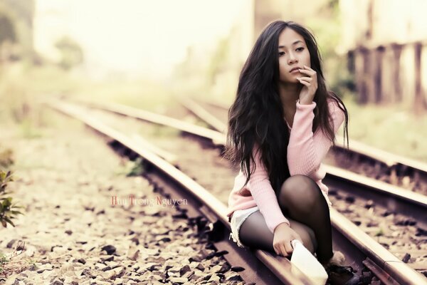 Fille triste assise sur les rails