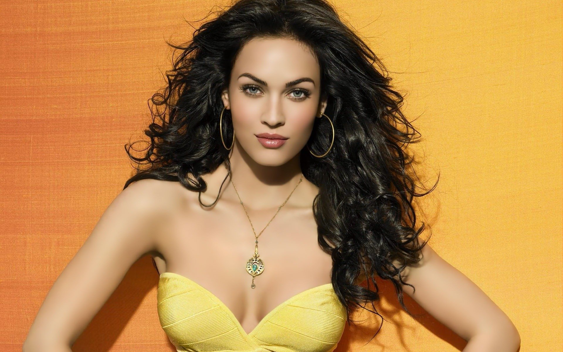 megan fox ragazza modello attrice viso sguardo capelli riccioli ciondolo gioielli orecchini sfondo