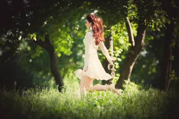 The girl runs with a flying gait through the grass