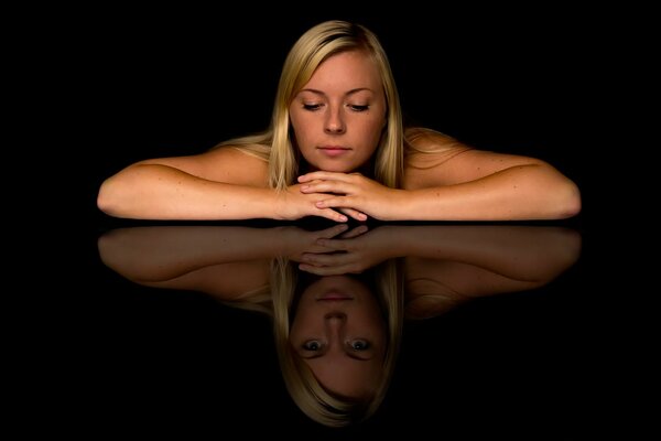 The girl looks at the reflection of the table, a different look