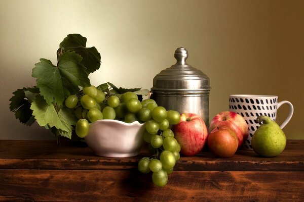 Bodegón con frutas y uvas en un jarrón sobre la mesa