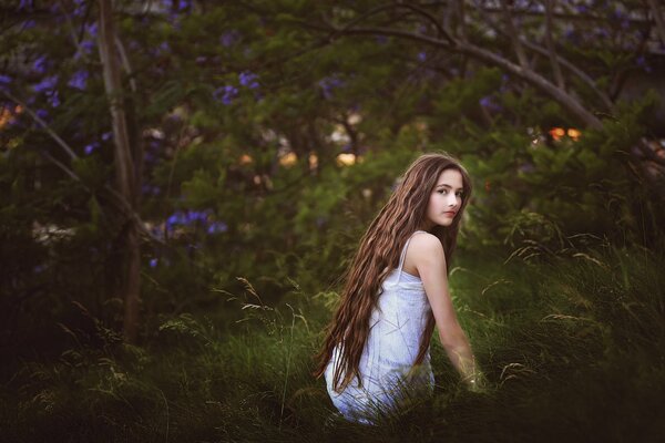 A cute teenage girl against the background of virgin nature pleases with her simplicity and naivety