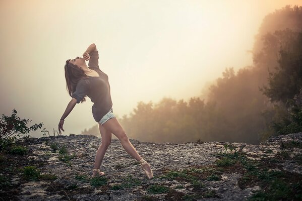 Danza della ragazza della ballerina sul bordo della scogliera