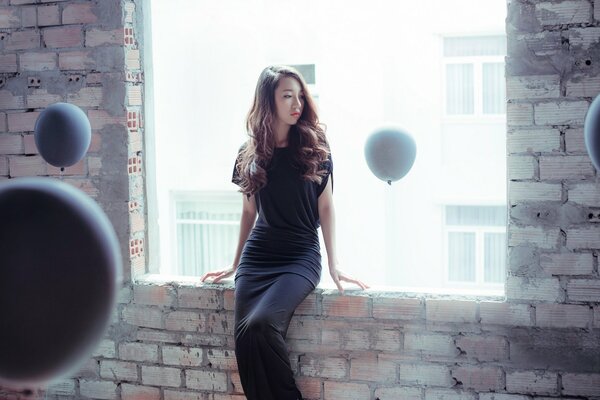Oriental girl in a long black dress and white balloons