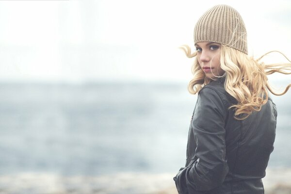 Sandra in a beanie with her hair down by the lake