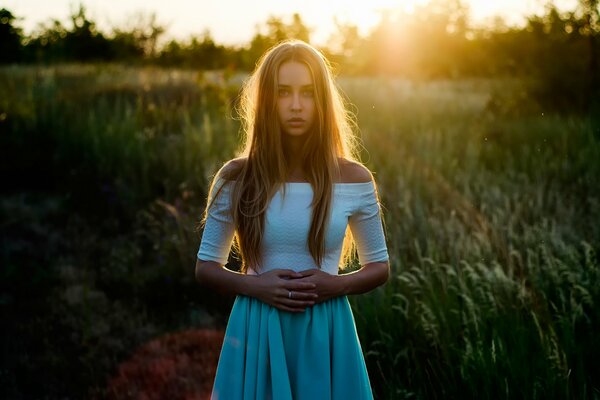 A girl in a meadow is illuminated by the rays of the sun