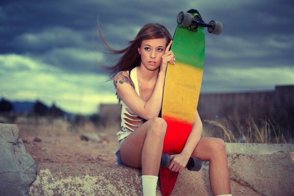 Jeune fille assise avec une planche à roulettes dans les mains