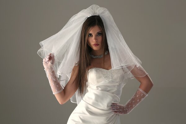 Long-haired bride in a wedding dress, veil and transparent gloves