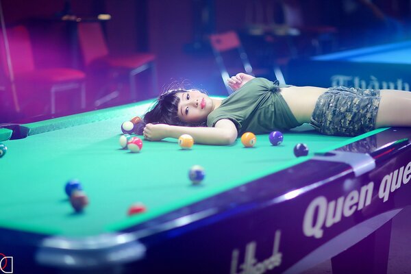 Fille sur la table parmi les boules de billard