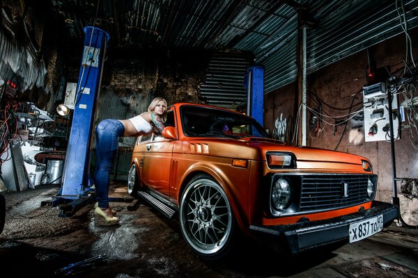 Blonde girl and orange VAZ on a lift