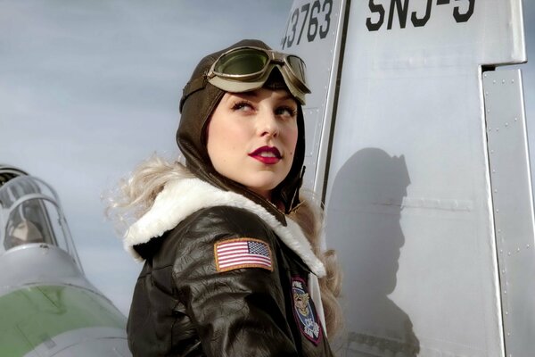 Chica en uniforme de aviación sobre un fondo gris