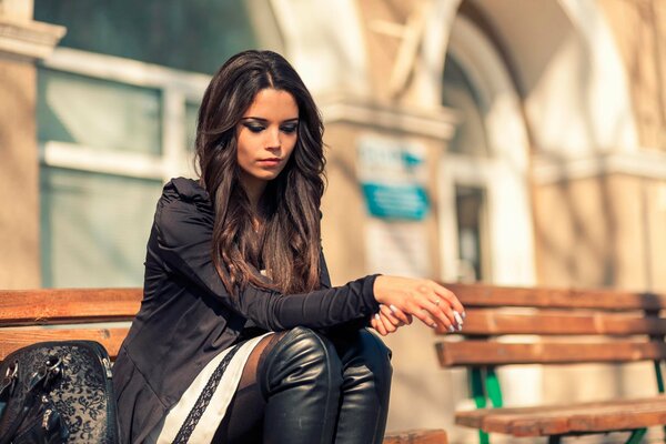 A young girl is bored on a bench