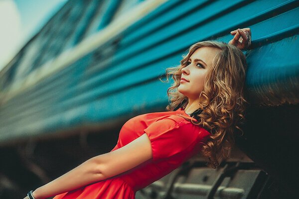 Composition a girl in a red dress on the background of a train