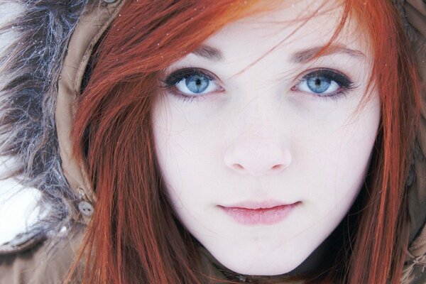 A red-haired girl with blue eyes in a hood