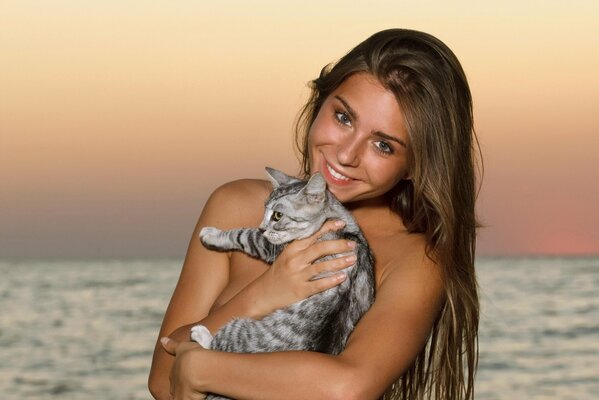 Fille souriante aux cheveux longs avec chat sur fond de mer