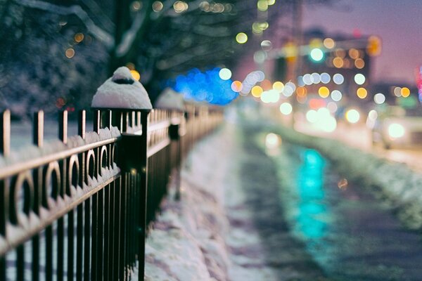 An iron fence stands along the sidewalk