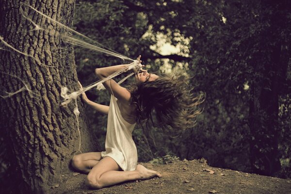 Disheveled girl in a web in the forest