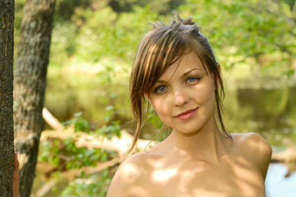 Emily is a brown-haired girl with bare shoulders against the background of nature summer landscape