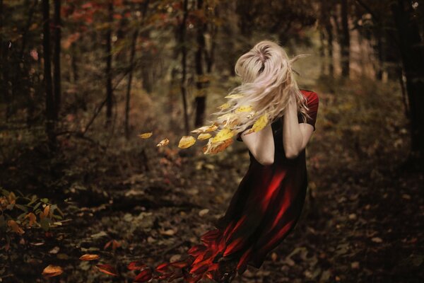 A girl in a red dress in autumn in the forest