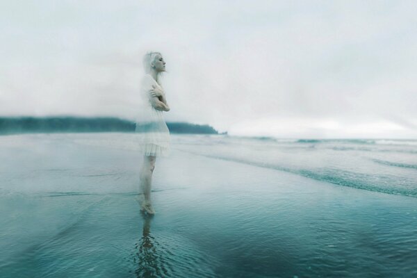 Translucent silhouette of a blonde in a white dress standing on the shore of a gloomy sea