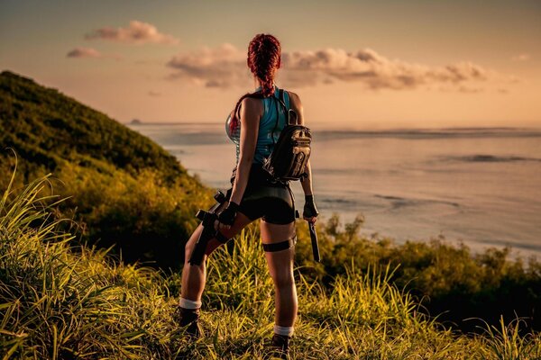 Lara Crofts Cosplay mit Waffen in der Natur