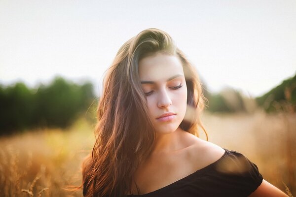 Hermosa misteriosa chica con pelo voluminoso en el fondo del campo