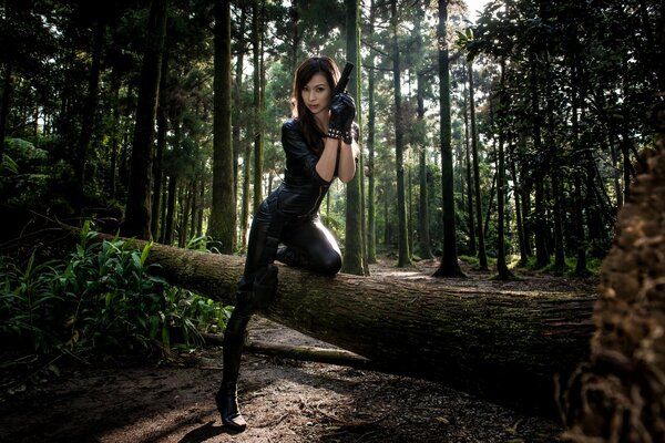 A girl with a gun is standing on a fallen tree