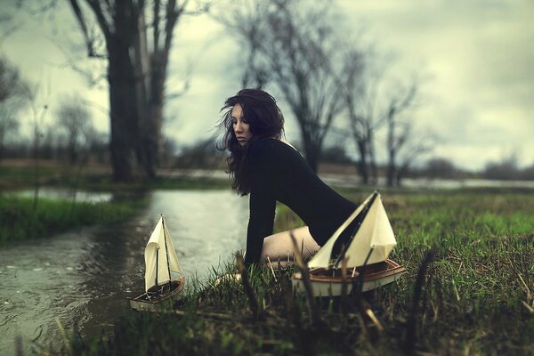 La chica del vestido negro lanza barcos por el río