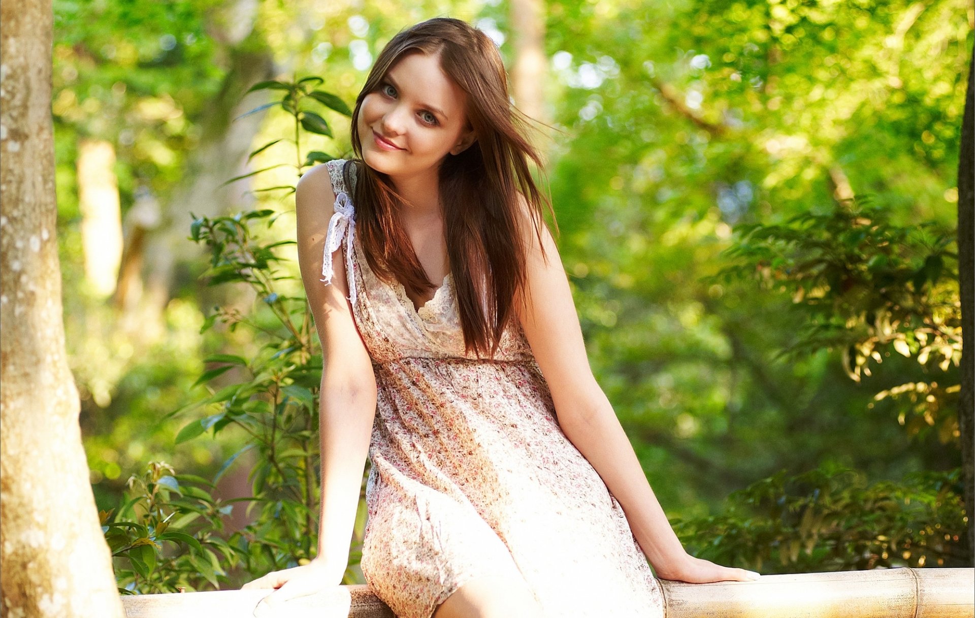 emily fille brune vue sourire boucles brise robe arbre bûche bokeh feuillage arc