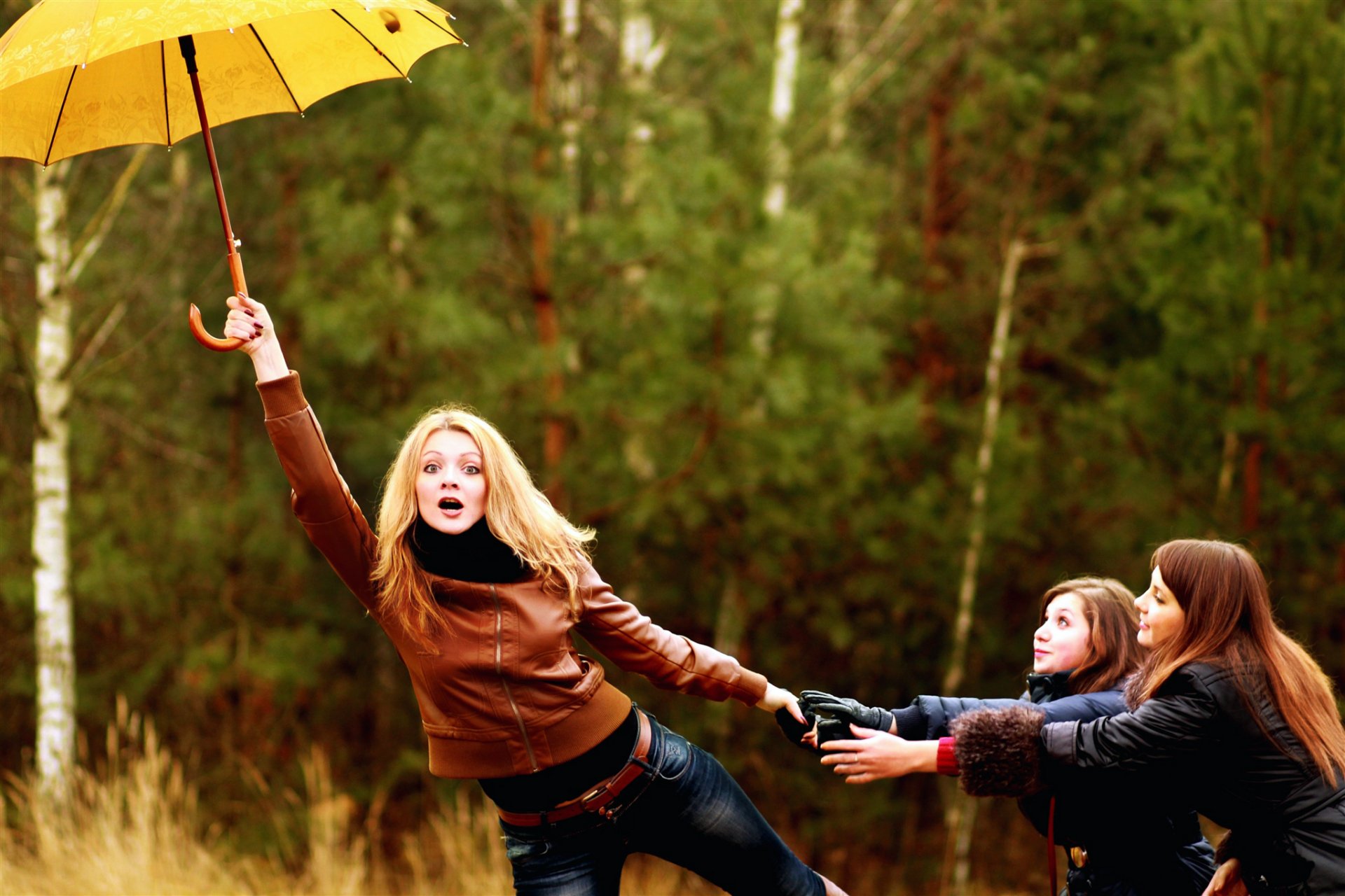 girls blonde brown-haired trio umbrella wind nature forest