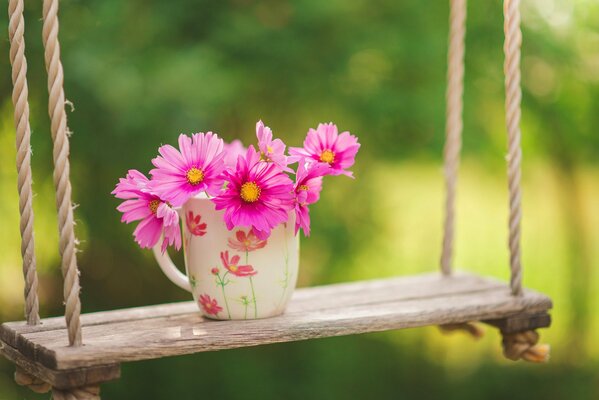 Tasse mit Blumenstrauß auf Kinderschaukel